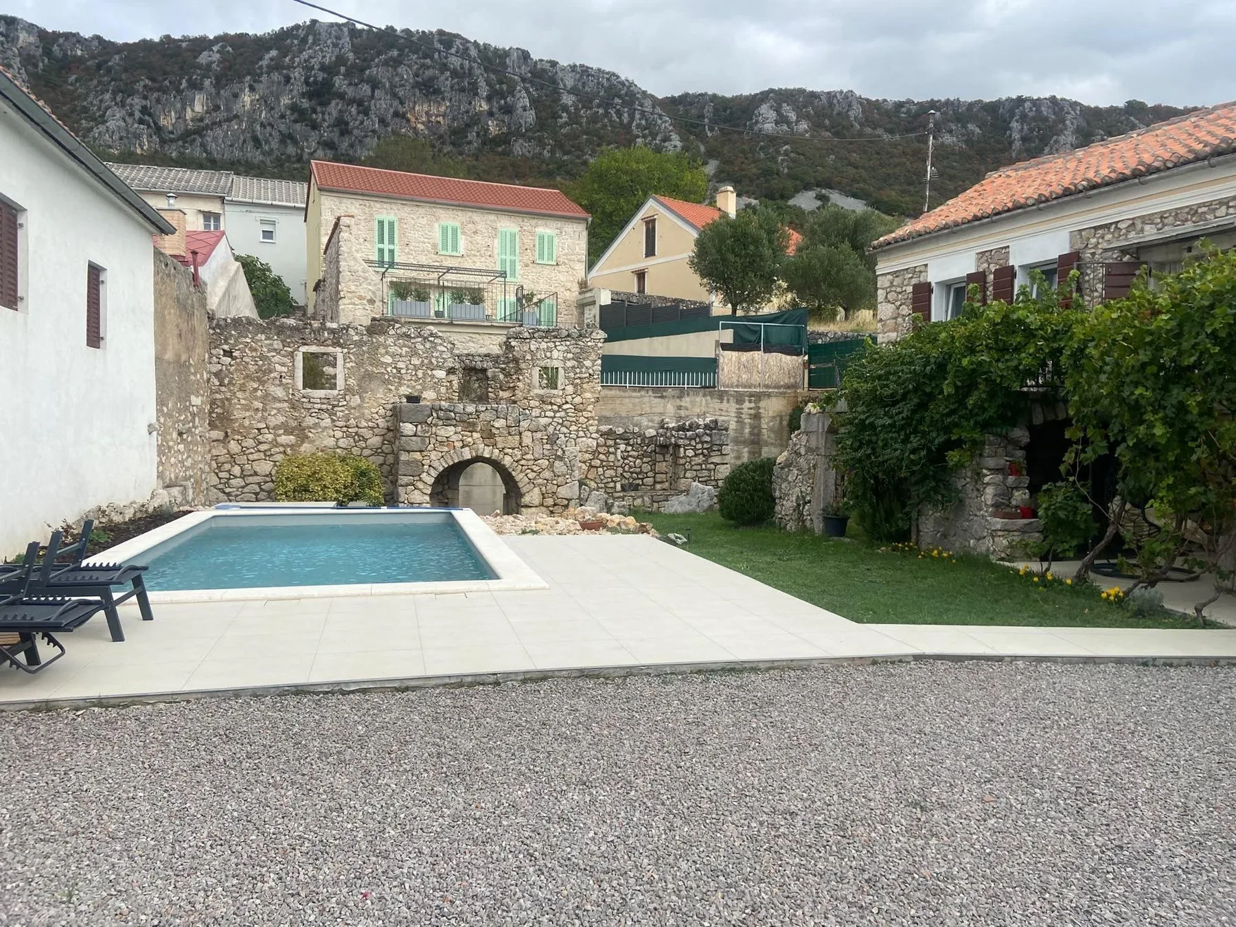 The pool in the courtyard, the ruin’s stone arch behind it and the village below the mountain