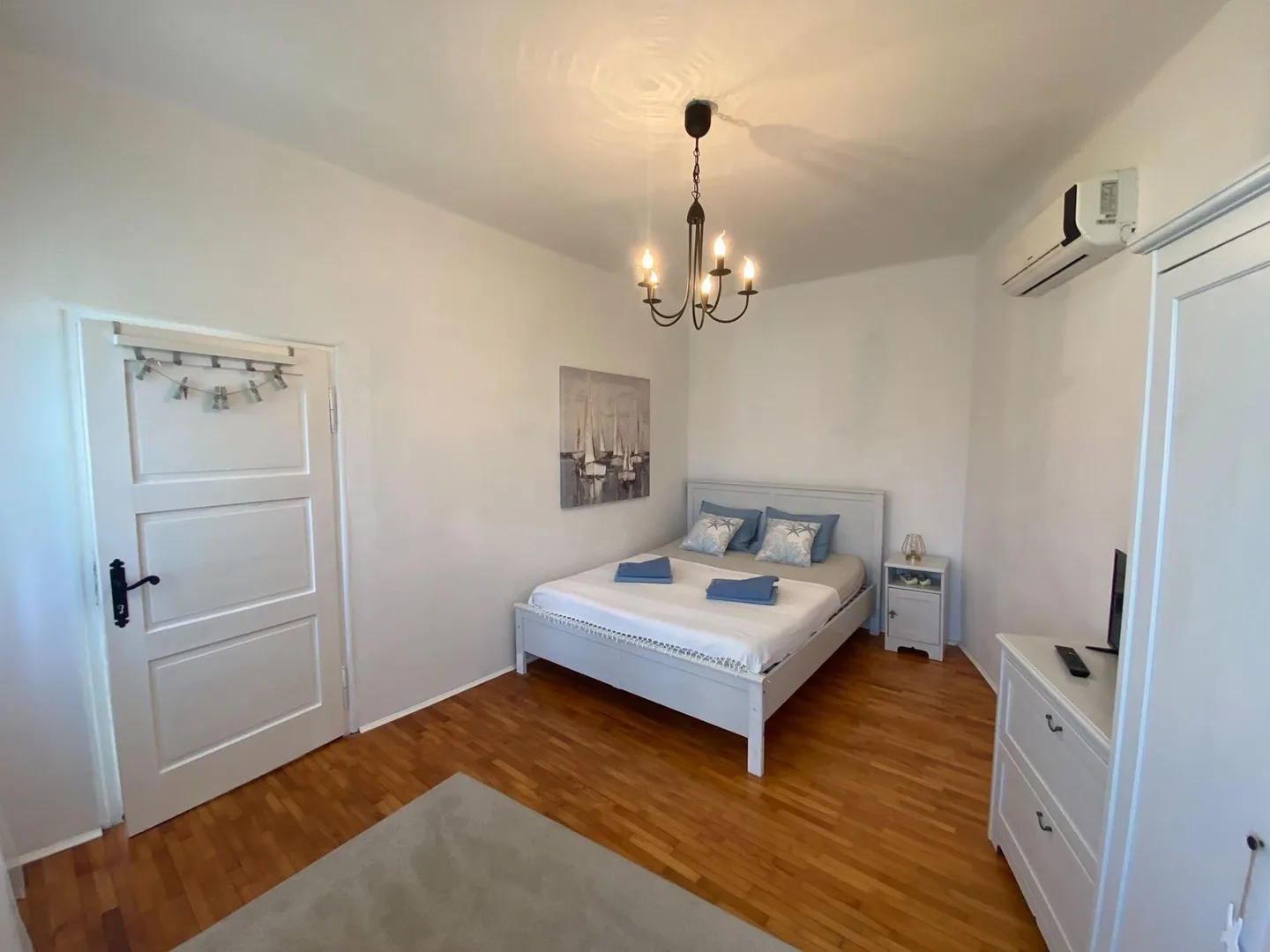 The whole room from the door: bed, chandelier and air conditioning