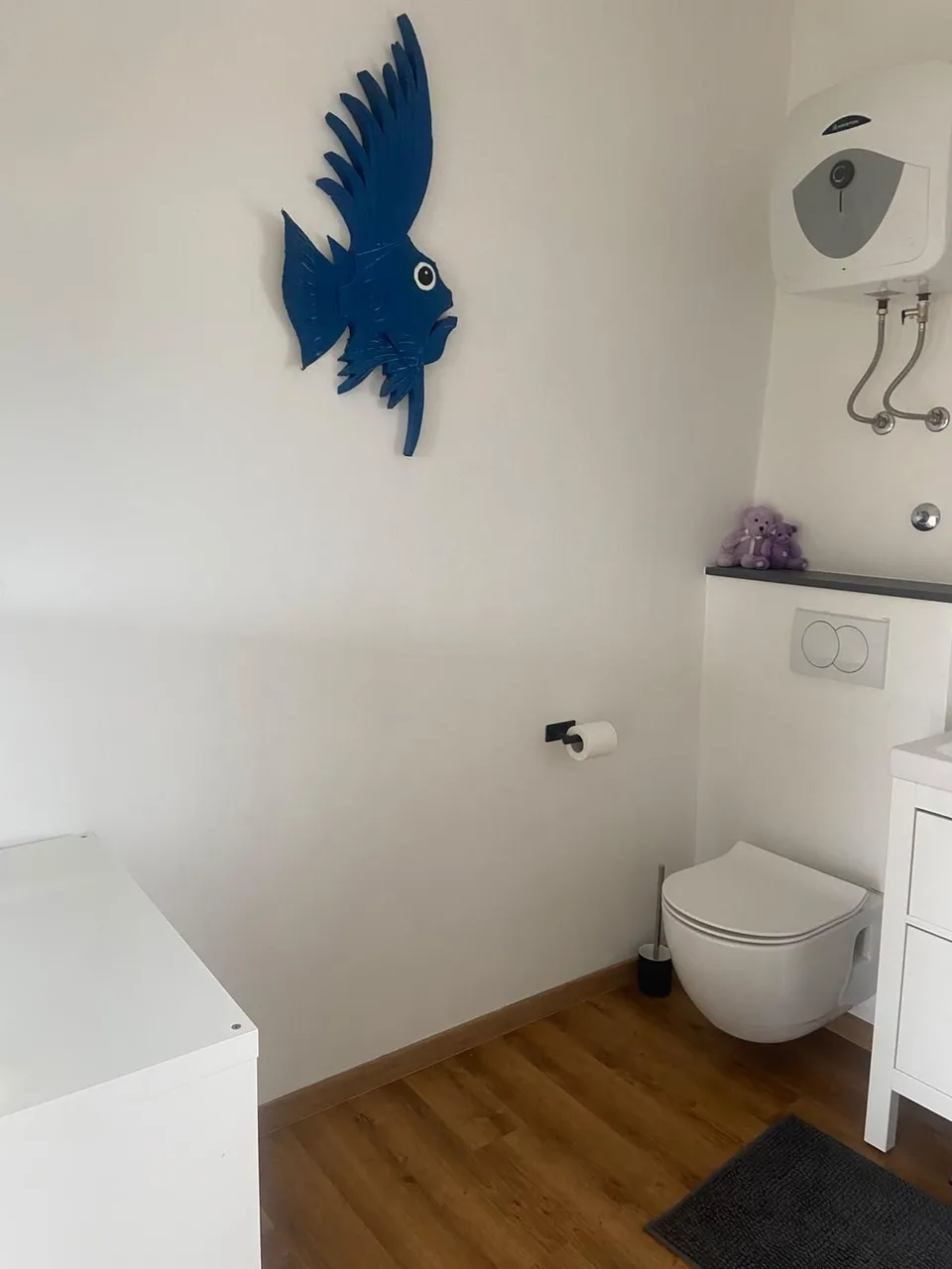 A wall-hung toilet and a blue bird on the wall