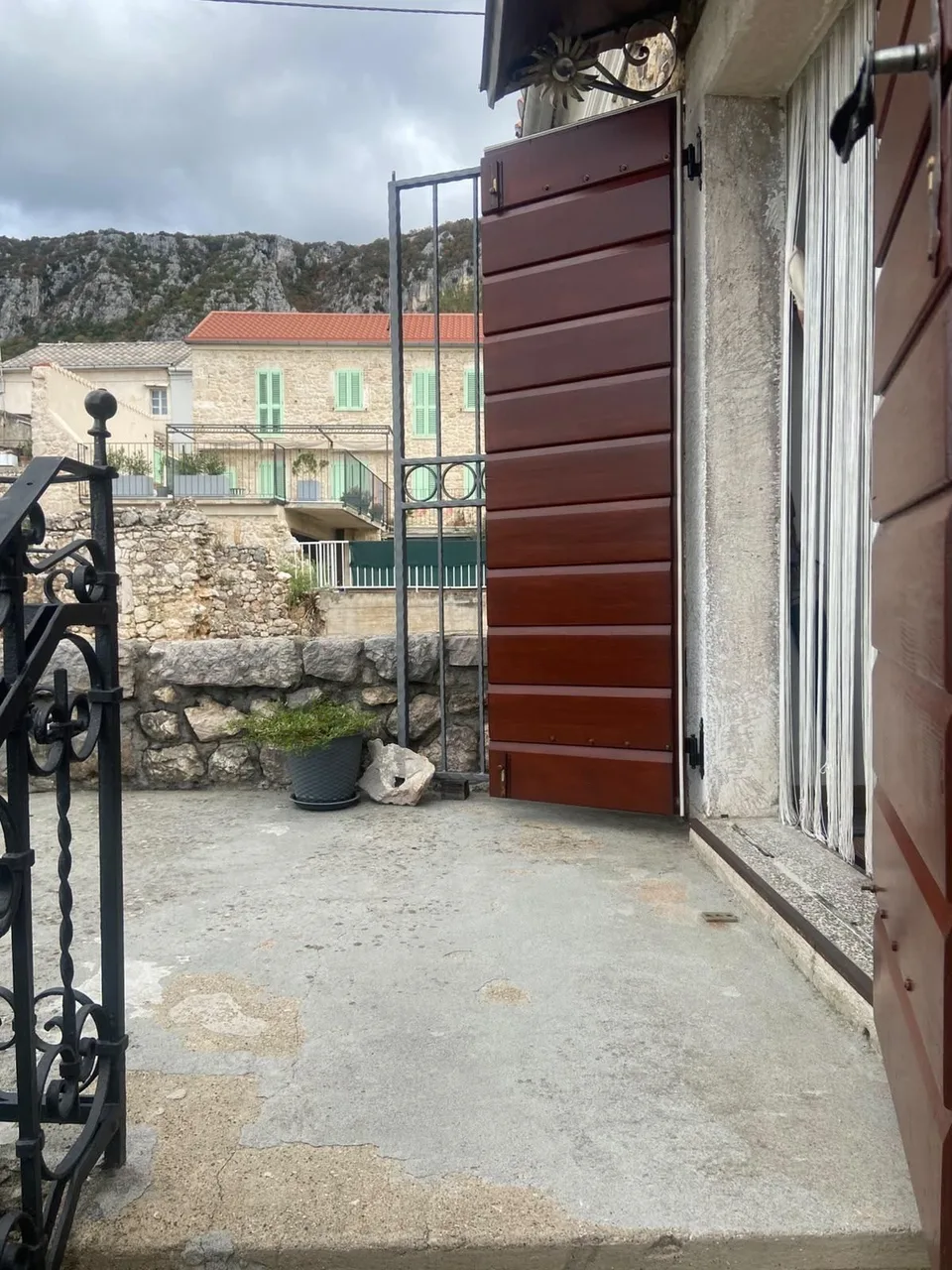 The balcony at the top of the stairs, the door with red shutters